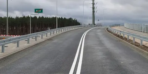 Droga ekspresowa jednojezdniowa z podwójną białą linią, znakiem Ruda i barierami ochronnymi.