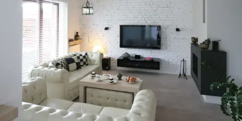 Nowoczesny salon z sofą i stolikiem kawowym. Ściana z białej cegły aranżacje dodaje wnętrzu charakteru.