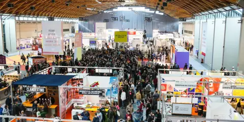 Folla in un padiglione fieristico, un'attrazione beer&food con stand e degustazioni.