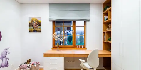 Kolorowa ściana nad biurkiem dziecka z obrazem domu na drzewie i latającymi balonami.