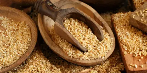 Kasza bulgur w drewnianych misach, gotowa do spożycia. Niski indeks glikemiczny sprawia, że jest zdrowym wyborem.