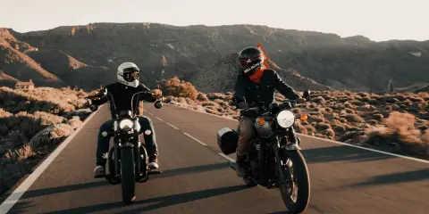Dwóch motocyklistów w stylowym ubraniu na motor turystyczny przemierza pustynną drogę.