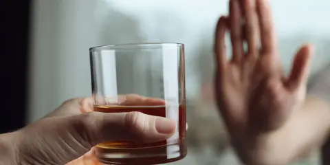 Dłoń odrzuca szklankę z alkoholem, symbolizując decyzję o zerwaniu z nałogiem. To koniec drogi, która mogła prowadzić do zgonu po esperalu.