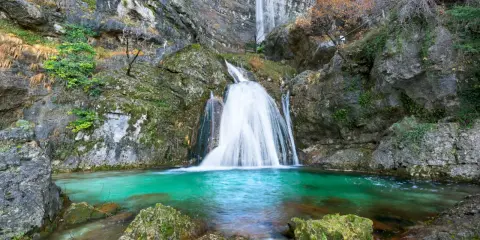 Impresionantes cascadas en Albacete, con agua turquesa cayendo por rocas cubiertas de musgo. Un paisaje natural de ensueño.