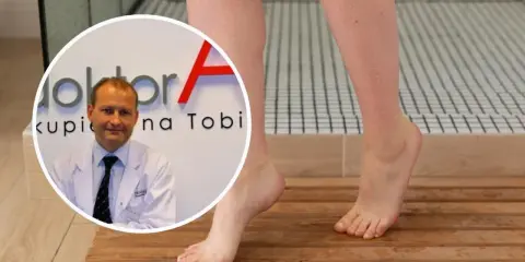 Lekarz w białym kitlu obok stóp z uczuciem ciężkich nóg. Woda na skórze sugeruje problem z krążeniem.