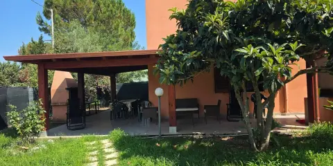 Veranda con tavolo e sedie, barbecue e alberi da frutto. Un angolo di pace tra i migliori agriturismi Sardegna sud.