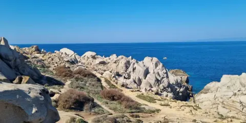 Felsige Küste am Capo Testa, Sardinien, mit tiefblauem Meer und klarem Himmel.