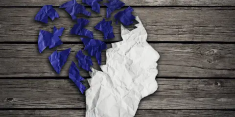 Zgnieciona papierowa głowa, której fragmenty odlatują, symbolizuje problem z pamięcią krótkotrwałą.