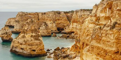 Ensam vandring på egen hand i Portugal längs en dramatisk kustlinje med gyllene klippor och turkost vatten.