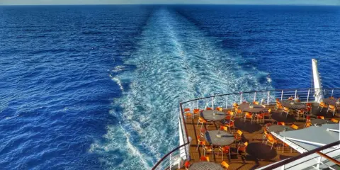 Scia di un'imbarcazione Costa Crociere, con tavoli e sedie arancioni sul ponte, ideale per escursioni libere in mare aperto.