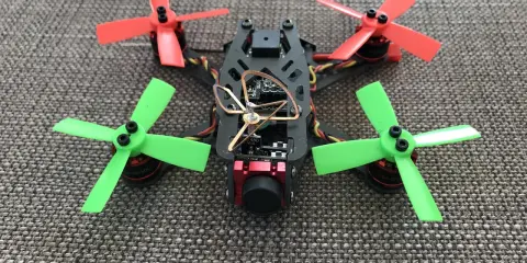 Ein kleiner, bunter Quadrocopter mit roten und grünen Propellern, bereit für aufregendes FPV fliegen.