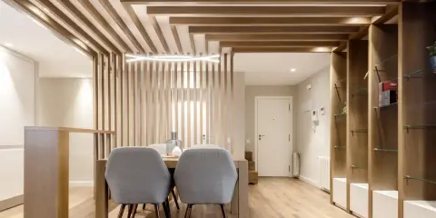 Comedor moderno con separador de listones de madera y estanterías. Preguntarse cuanto se tarda en tirar un tabique es irrelevante aquí.