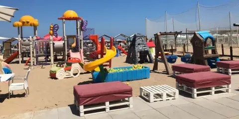 Area giochi per bambini sulla sabbia, con scivoli, altalene e piscina di palline. Un angolo di divertimento al Regina Beach Cattolica.