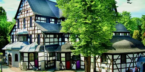 Kościół Pokoju w Świdnicy, z charakterystyczną szachulcową architekturą, otoczony zielenią.