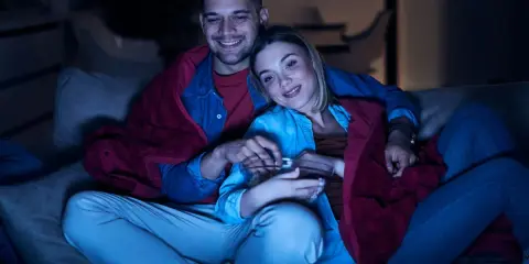 Para spędza miły wieczór, otulona kocem, oglądając lekkie filmy na wieczór i jedząc popcorn.