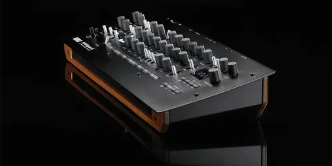 Synthétiseur Korg minilogue xd noir avec finitions bois, posé sur une surface réfléchissante.