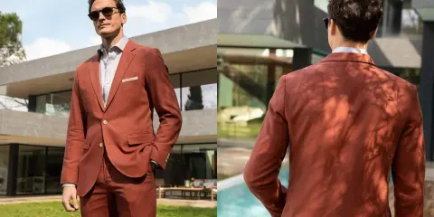 Man in a rust-colored suit, embodying a festive dress code for males, poses outdoors by a modern house and pool.