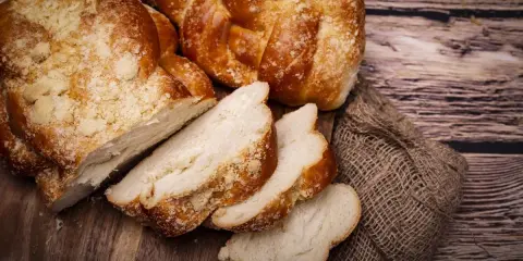 Puszyste ciasto drożdżowe, pokrojone w kromki, na drewnianej desce. Dowiedz się, jak przechowywać ciasto drożdżowe, by było świeże.