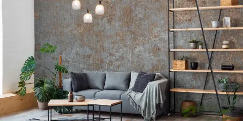 Nowoczesny salon z szarą sofą, stolikami kawowymi i regałem. W tle industrialna fototapeta ze zdjęcia.