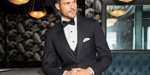 A man in a sharp tuxedo, perfect for any black tie event or formal occasion. He embodies the classic tuxedo dress code with a crisp white shirt and bow tie.
