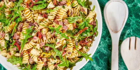 Pyszna sałatka z makaronem fusilli, rukolą, suszonymi pomidorami, oliwkami i kawałkami salami. Idealna na letnie dni.