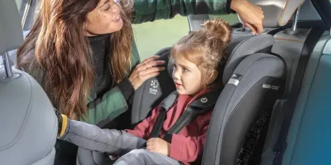 Mama poprawia zagłówek w foteliku samochodowym 9-36 dla swojej córki.
