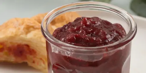 Słoiczek z konfiturą z płatków róży obok ciastka.