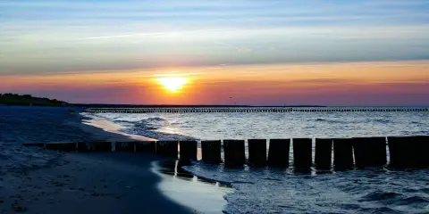 Zachód słońca nad Bałtykiem, falochrony i plaża w Sarbinowie. Piękne atrakcje Sarbinowo.