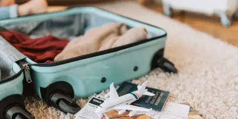 Bagaż podręczny Pegasus Airlines gotowy do podróży. W walizce ubrania, obok paszport, bilety i model samolotu.