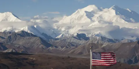 US-Flagge vor schneebedeckten Bergen des Denali Nationalparks.