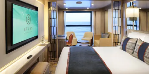 Interni lussuosi di una cabina garantita Costa Crociere con letto comodo, divanetti, scrivania e TV. Vista mare dalla finestra.