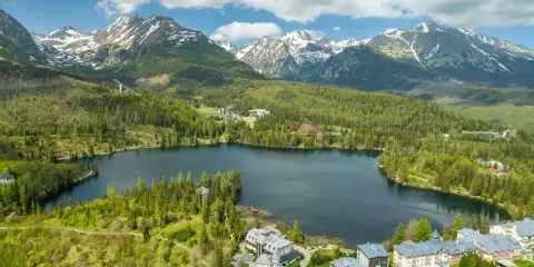 Malownicze jezioro otoczone lasem i górami, z hotelami w tle. Słowacja atrakcje turystyczne w pełnej krasie.