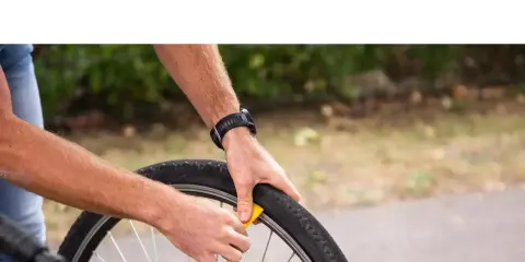 Rowerzysta wymienia oponę. Zastanawiasz się, gdzie wyrzucić opony rowerowe? Sprawdź lokalne punkty zbiórki odpadów.