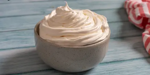 Nata montada perfecta en un cuenco gris, lista para decorar postres.