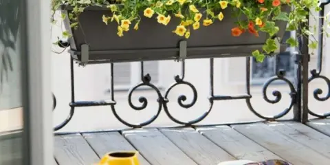 Jardinière extérieure fleurie sur un balcon, une belle idée composition pour un coin lecture avec un livre et des lunettes.
