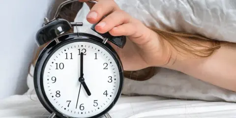Ręka wyłącza budzik. Jest 5:00, a 0303 znaczenie tego czasu to nowy początek dnia.