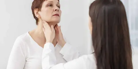 Medico esamina il collo di una paziente, possibile indicazione per una scintigrafia tiroidea.