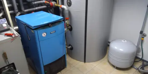 Niebieski piec i duży zasobnik wody, idealne rozwiązanie jaki bufor do domu 150m2. Obok zbiornik wyrównawczy.