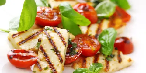 Grillowany serek halloumi z pomidorkami koktajlowymi i bazylią, apetyczna przekąska.