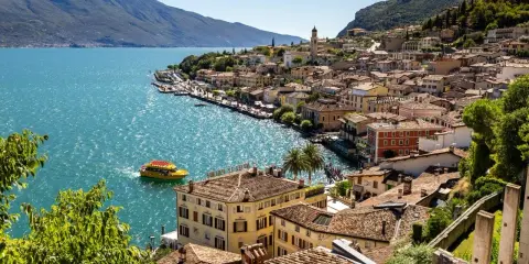 Limone sul Garda cosa vedere: pittoresca cittadina sul lago, con case colorate, un battello giallo e montagne sullo sfondo.