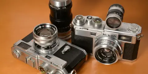 Kolekcja aparatów Nikon z obiektywami. Dwa modele Nikon z lat 50. i 60. XX wieku, każdy z innym obiektywem Nikkor.