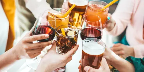 Ręce wznoszą kieliszki z winem, drinkami i piwem, celebrując wspólne chwile.