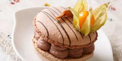 Un délicieux macaron chocolat au lait, garni de crème onctueuse et décoré d'une physalis orangée.