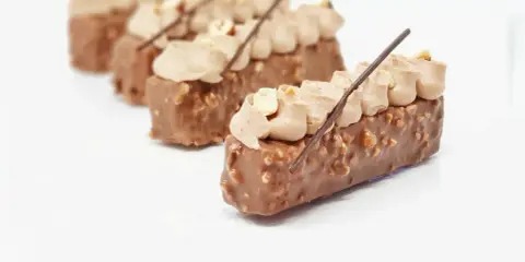 Délicieux entremets chocolat praliné, recouverts de noisettes croquantes et surmontés d'une crème onctueuse.