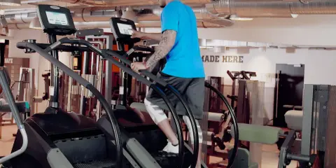 Mann trainiert auf einem Stairmaster im Fitnessstudio.