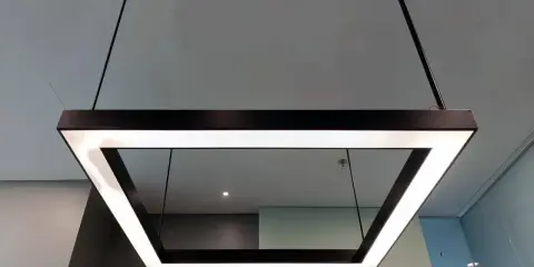 Nowoczesna podsufitka led w kształcie kwadratu, zawieszona na cienkich linkach, tworzy minimalistyczną i elegancką przestrzeń.