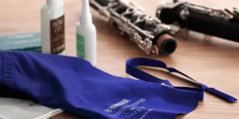 Ensemble pour l'entretien d'une clarinette : deux flacons d'huile, une housse bleue et des parties de l'instrument.