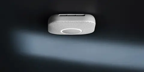 En vit Google Nest Protect-rökdetektor med en cirkulär ljusring monterad i taket.