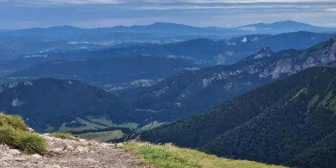 Kamienista ścieżka prowadzi przez zielone zbocza w kierunku malowniczych gór Mała Fatra.