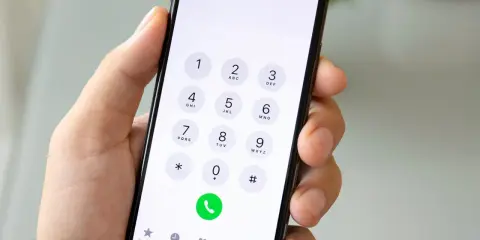 Dłoń trzyma smartfon z klawiaturą numeryczną. Chcesz wiedzieć, jak sprawdzić numer? Wpisz go na klawiaturze telefonu.